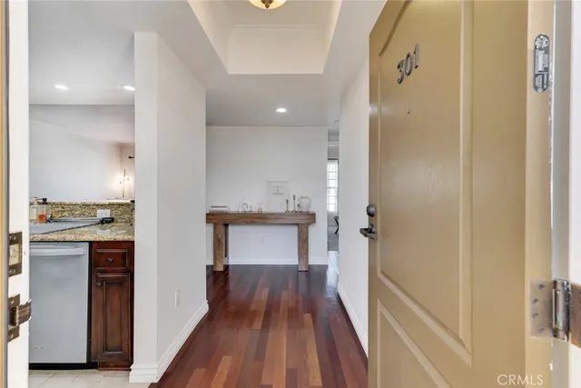 a view of a hallway with wooden floor and a bathroom