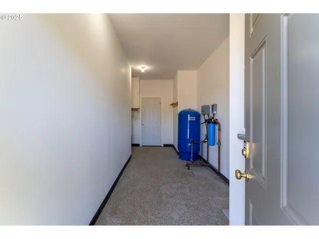 a view of a hallway with wooden floor and a bathroom