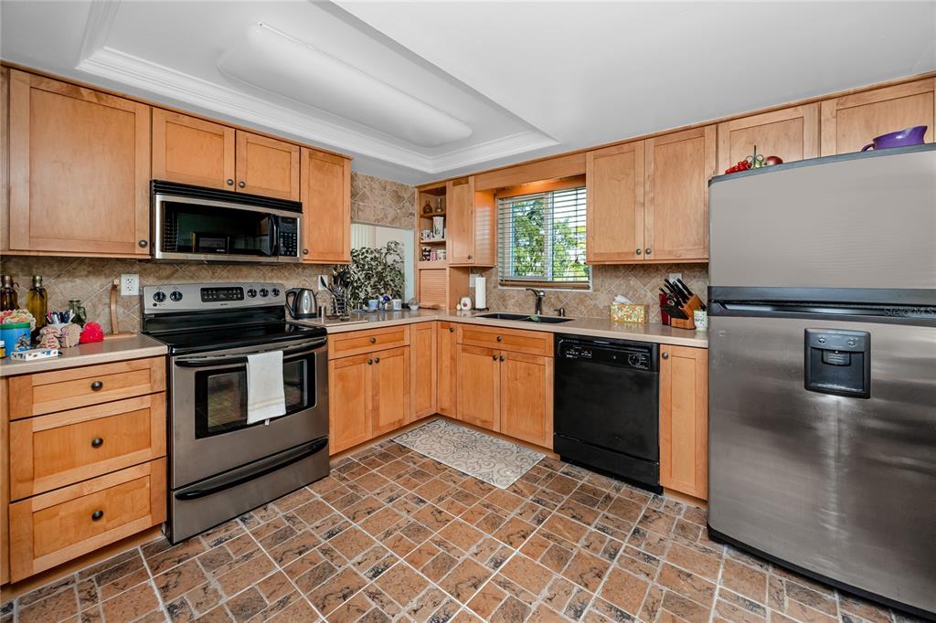 2737 Enterprise Road East, Unit 112 Clearwater, FL 33759 - Photo 11 of 43 a kitchen with granite countertop a sink stainless steel appliances and cabinets