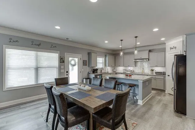 a kitchen with a dining table chairs and refrigerator
