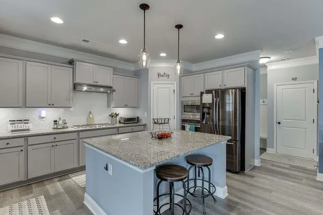 a kitchen with stainless steel appliances granite countertop a sink a stove a refrigerator and island with wooden floor