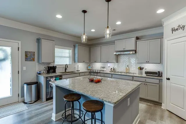a kitchen with a stove a sink a kitchen island with chairs and wooden cabinets