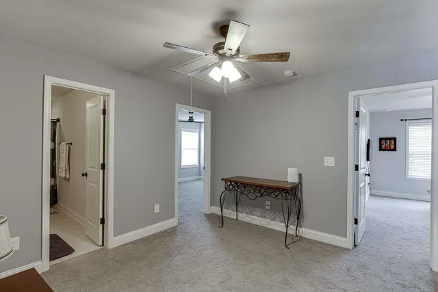 a view of a hallway with closet and a chandelier fan