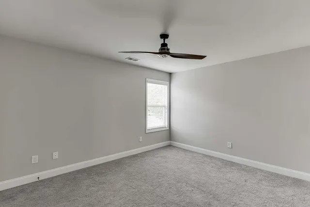 a view of an empty room and chandelier fan