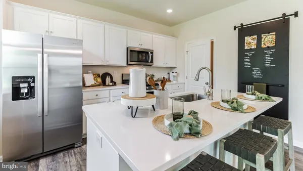 a kitchen with stainless steel appliances a refrigerator a sink a stove a table and chairs