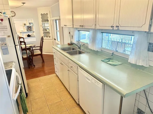 a kitchen with stainless steel appliances granite countertop a sink a stove white cabinets a dining table and chairs