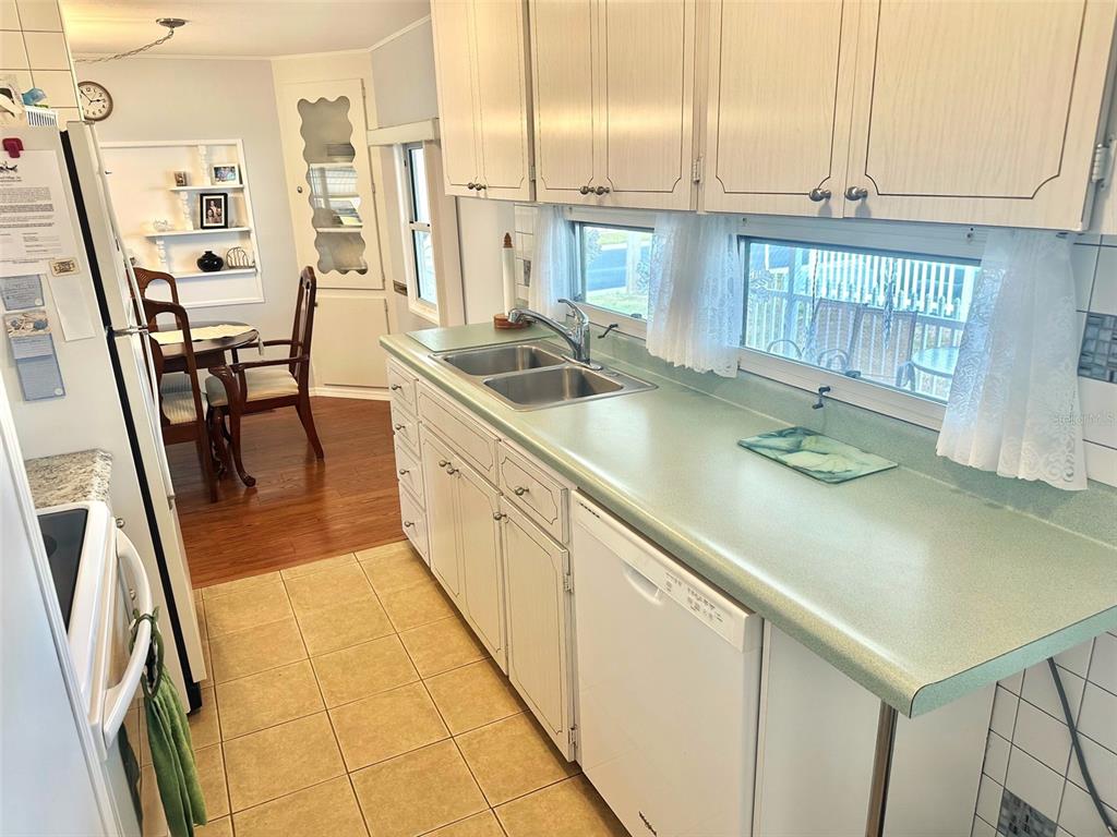 2000 East Bay Drive, Unit 102 Largo, FL 33771 - Photo 14 of 17 a kitchen with stainless steel appliances granite countertop a sink a stove white cabinets a dining table and chairs
