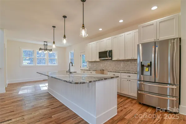 a kitchen with granite countertop a sink a counter space appliances and cabinets