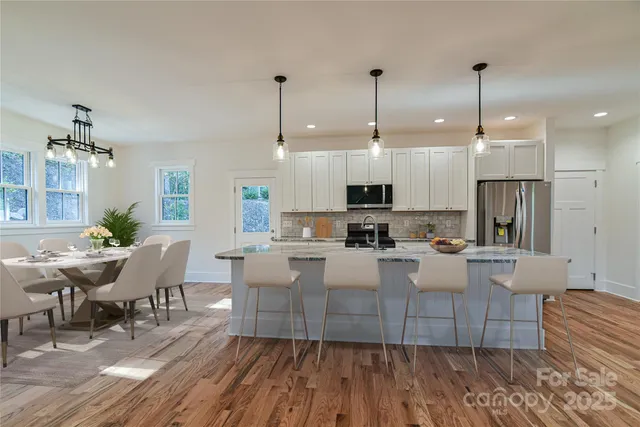 a large kitchen with cabinets wooden floor white stainless steel appliances and dining table
