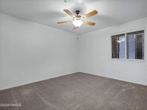 an empty room with window and ceiling fan