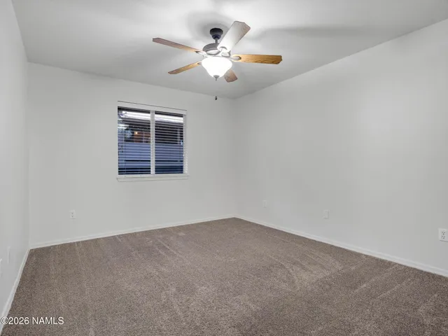 an empty room with windows and ceiling fan