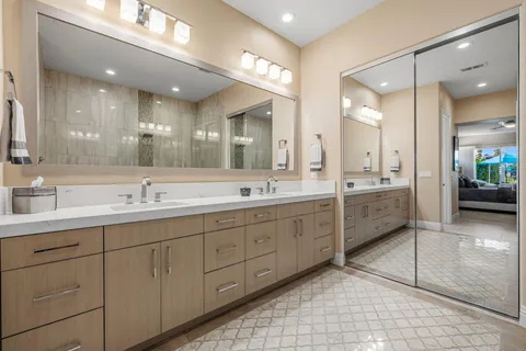 a bathroom with a granite countertop double vanity sink toilet and a mirror