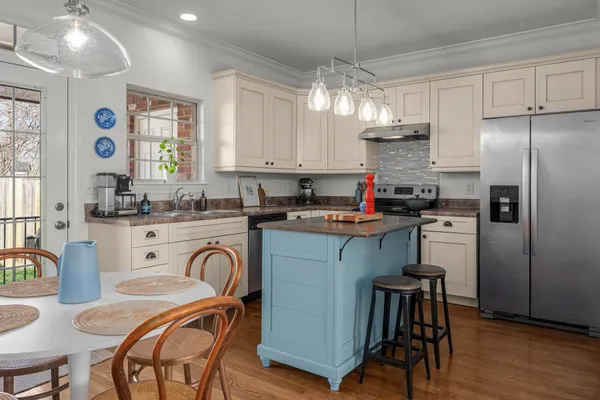 a kitchen with stainless steel appliances granite countertop a refrigerator a stove a sink dishwasher a dining table and chairs with wooden floor