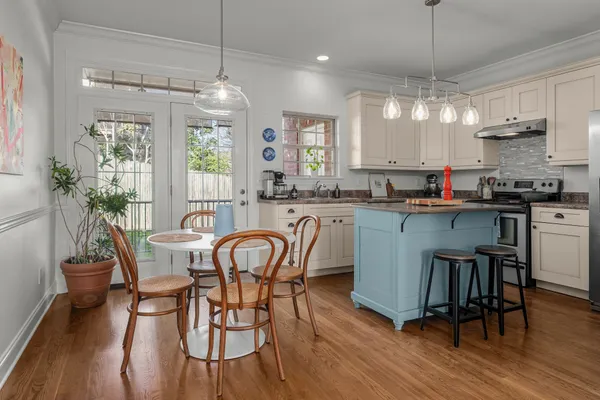 a kitchen with stainless steel appliances a dining table chairs stove and white cabinets