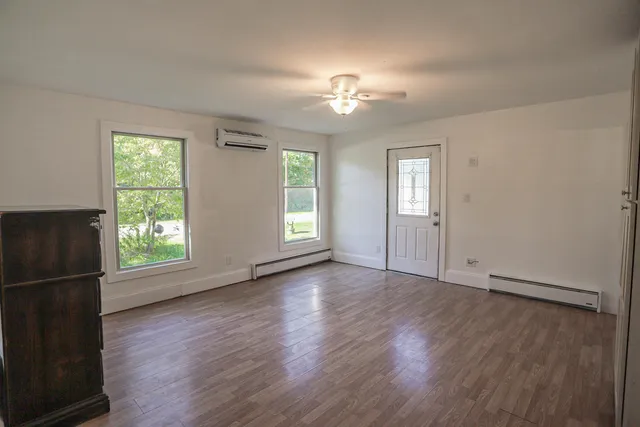 an empty room with wooden floor chandelier fan and windows