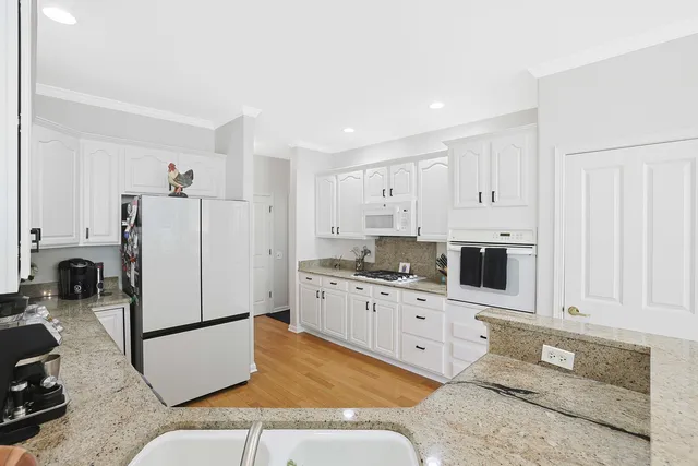 a kitchen with stainless steel appliances granite countertop a refrigerator sink stove and white cabinets