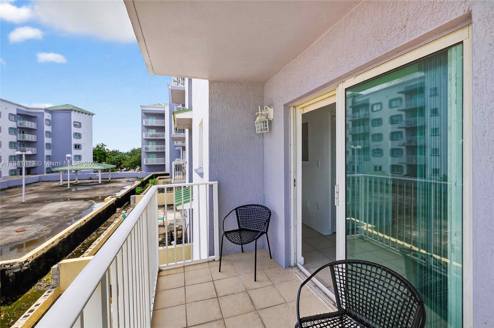 2475 Northwest 16th St Road, Unit 308 Miami, FL 33125 - Photo 21 of 25 a balcony with chairs and a stove