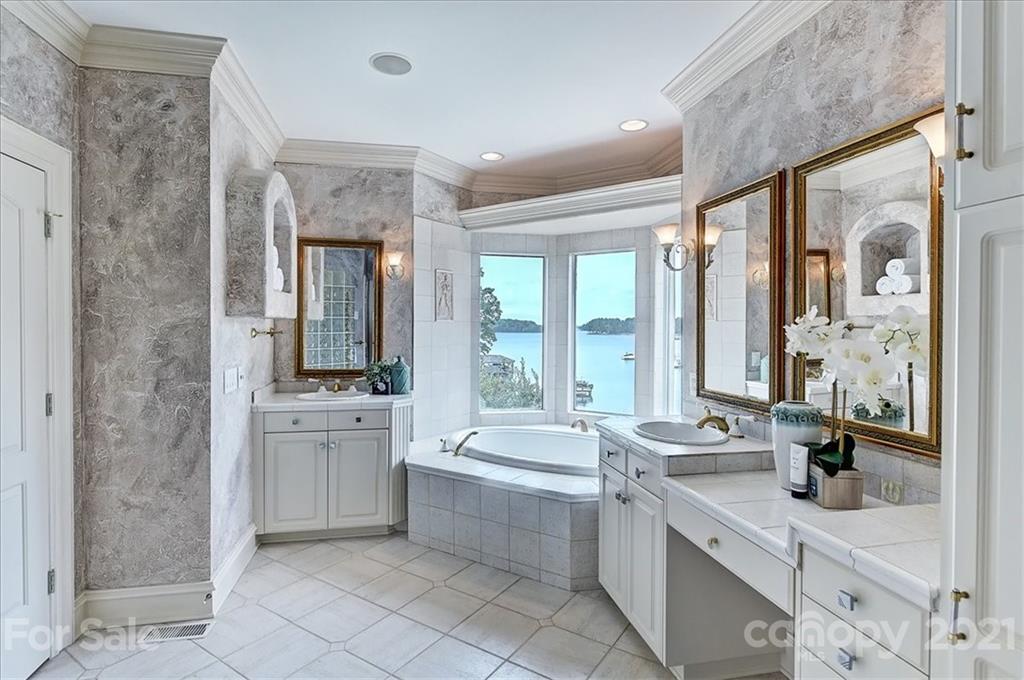 17519 Jetton Road, Unit 390 Cornelius, NC 28031 - Photo 13 of 31 a large bathroom with a double vanity sink a large mirror and a bathtub with shower