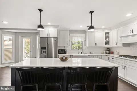 a kitchen with stainless steel appliances a stove top oven a refrigerator a sink and dishwasher with white cabinets
