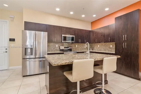 a kitchen with stainless steel appliances granite countertop a refrigerator a stove a sink and a microwave