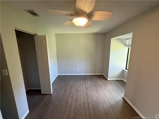 an empty room with wooden floor and fan