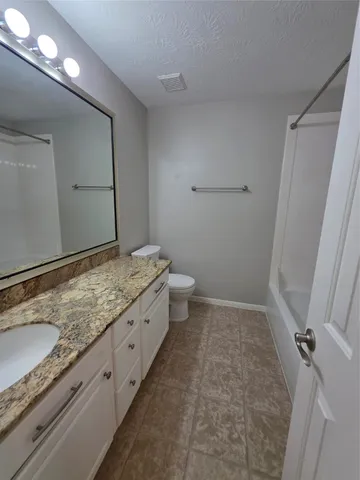 a bathroom with a granite countertop sink a toilet and a shower