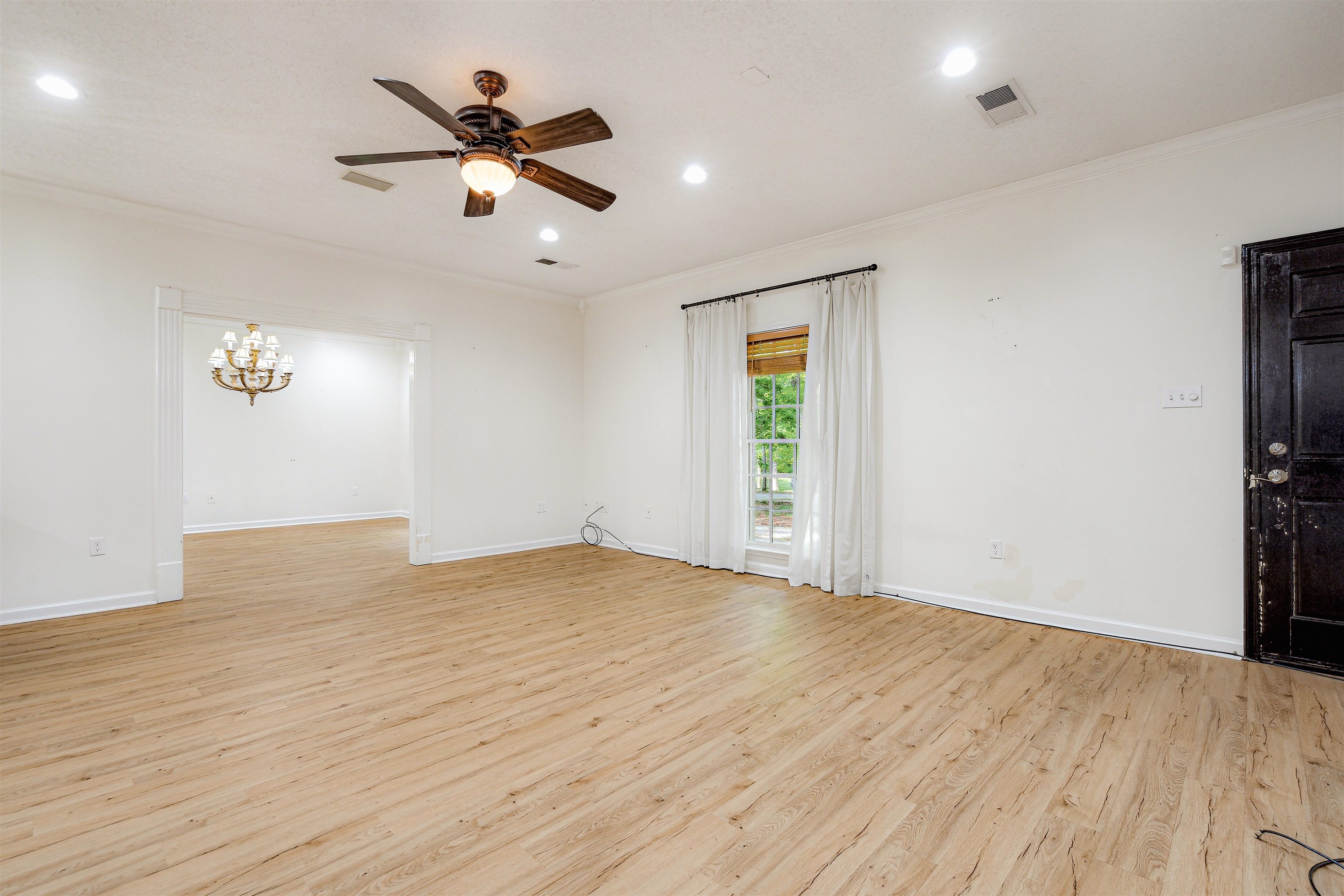 4020 Price Road Moscow, TN 38057 - Photo 10 of 35 Empty room featuring crown molding, ceiling fan with notable chandelier, light wood finished floors, and visible vents