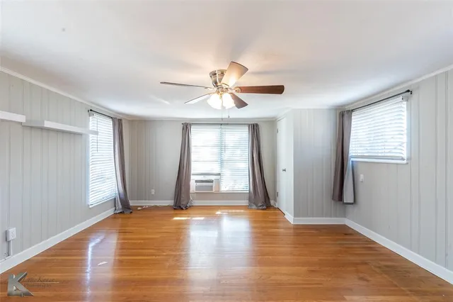 a view of empty room with wooden floor and fan
