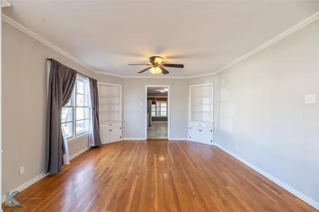 a view of an empty room with a window and wooden floor