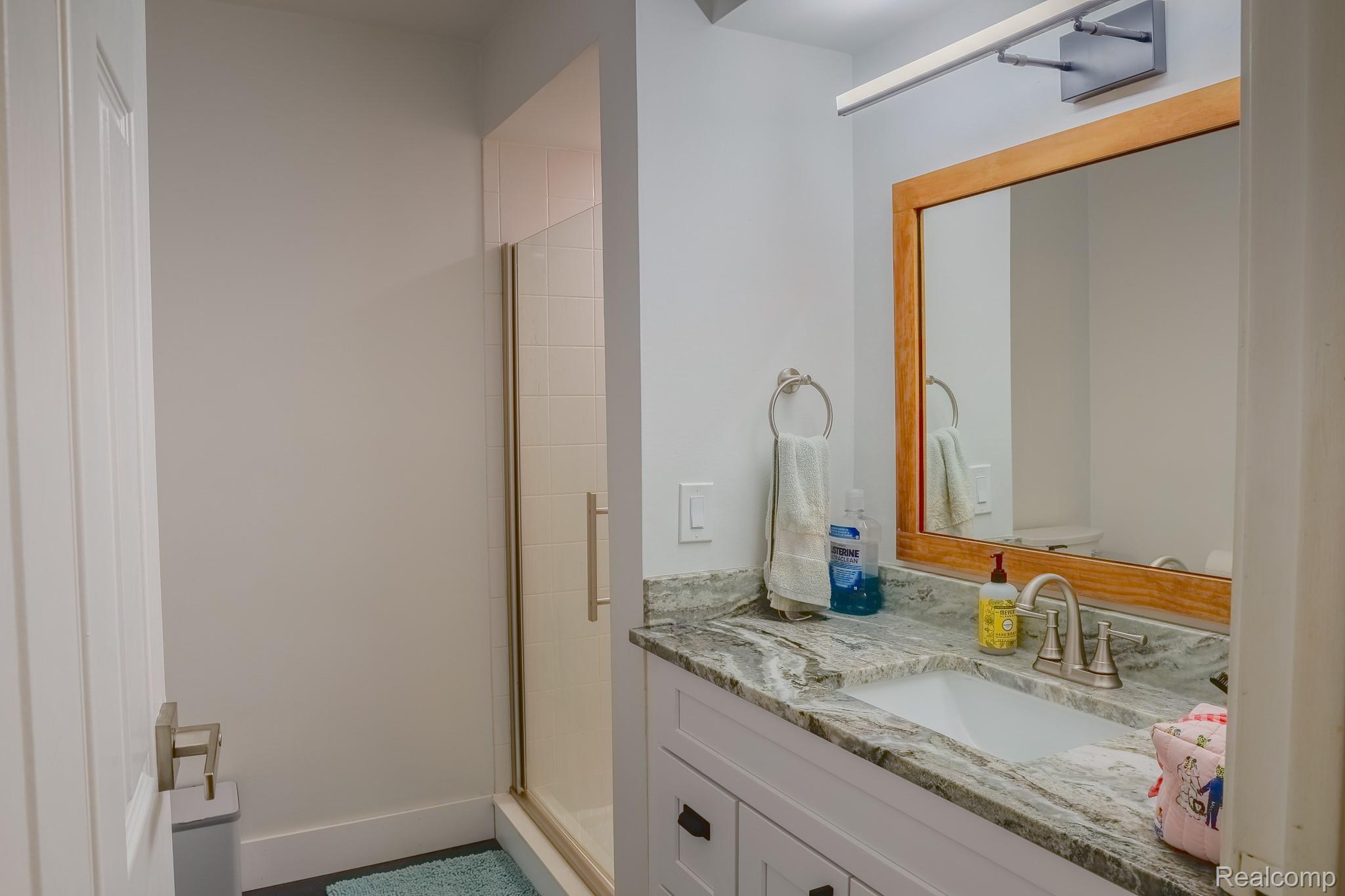 1989 Klingensmith Road, Unit 46 Bloomfield Hills, MI 48302 - Photo 32 of 41 Bathroom featuring a white vanity with dark hardware, a stone-finish countertop, and an undermount sink