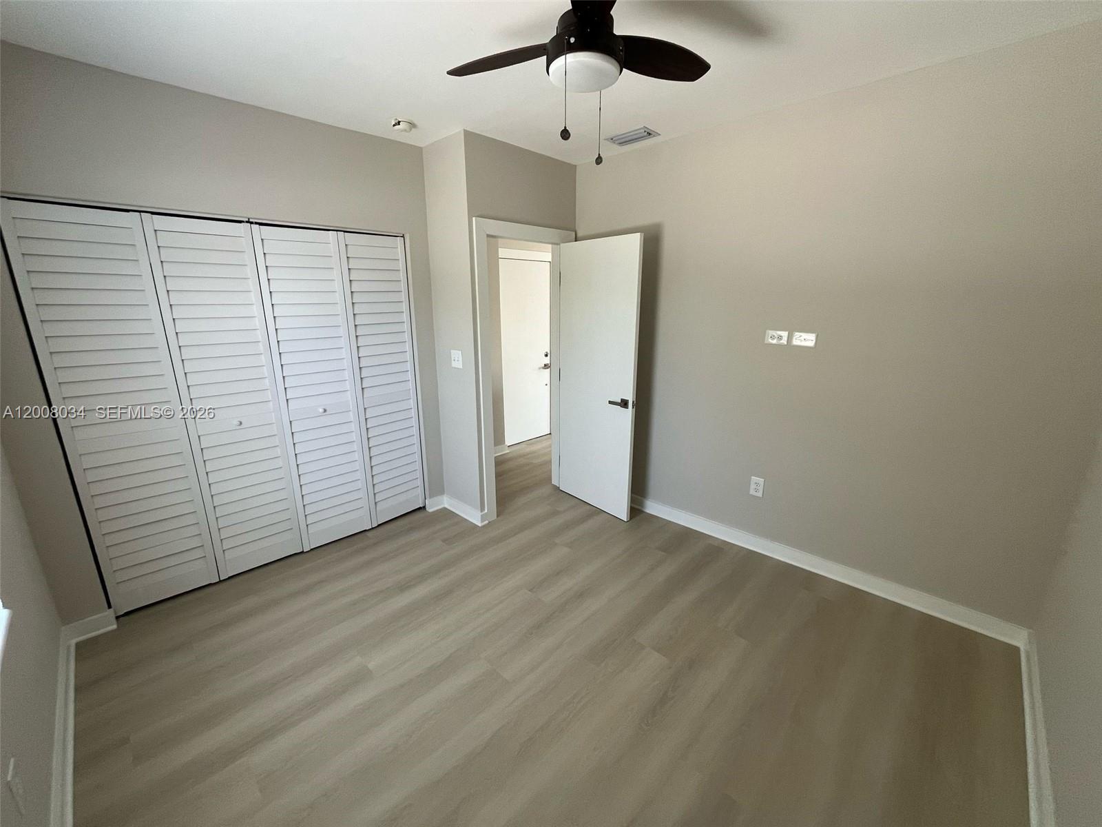 534 Southwest 6th Court, Unit 1 Miami, FL 33130 - Photo 6 of 10 an empty room with wooden floor closet and ceiling fan