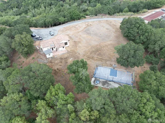 an aerial view of a house with a yard and trees all around