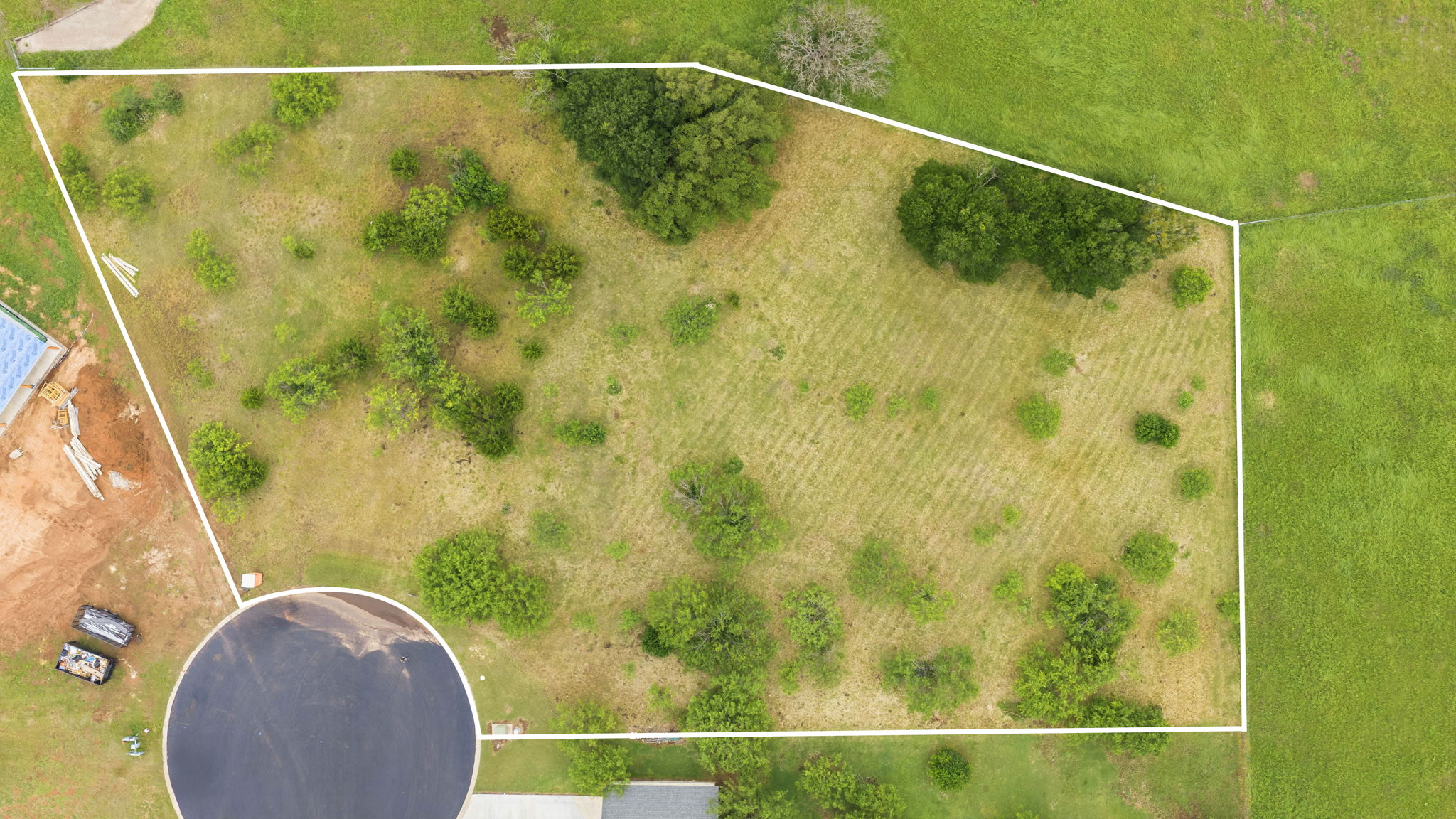 104 Round Up Circle Burnet, TX 78611 - Photo 2 of 23 Expansive land parcel outlined by a white boundary, featuring varied green vegetation and a partially cleared central area