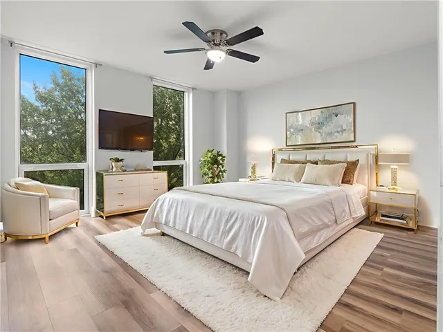 a bedroom with a large bed a flat tv screen and a dresser