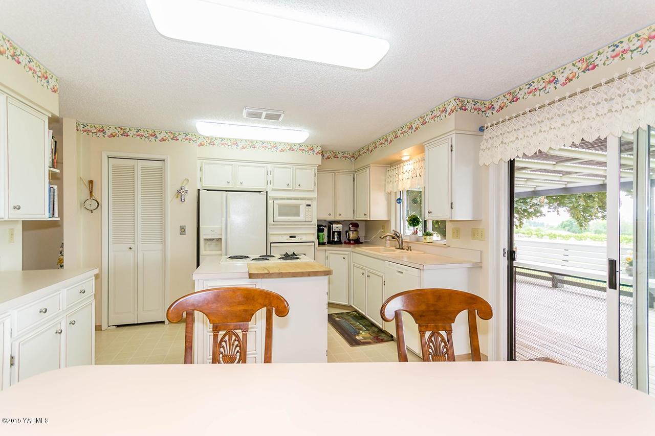 9530 Bittner Road Yakima, WA 98901 - Photo 8 of 28 a kitchen with stainless steel appliances granite countertop a refrigerator a stove and white cabinets with wooden floor