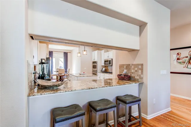 a dining hall with stainless steel appliances granite countertop a dining table and chairs