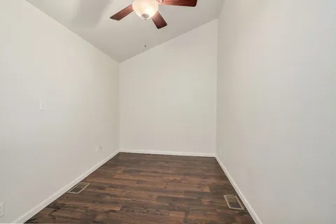 a view of an empty room with a chandelier fan