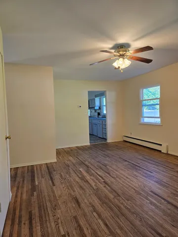 a view of empty room with wooden floor and fan