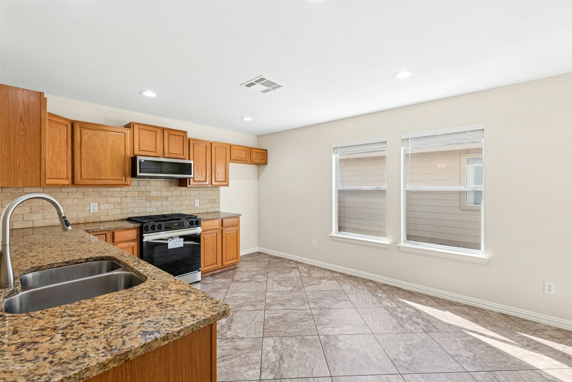 17913 Honey Locust Lane Elgin, TX 78621 - Photo 3 of 31 a kitchen with stainless steel appliances granite countertop a stove top oven a sink a counter space and cabinets