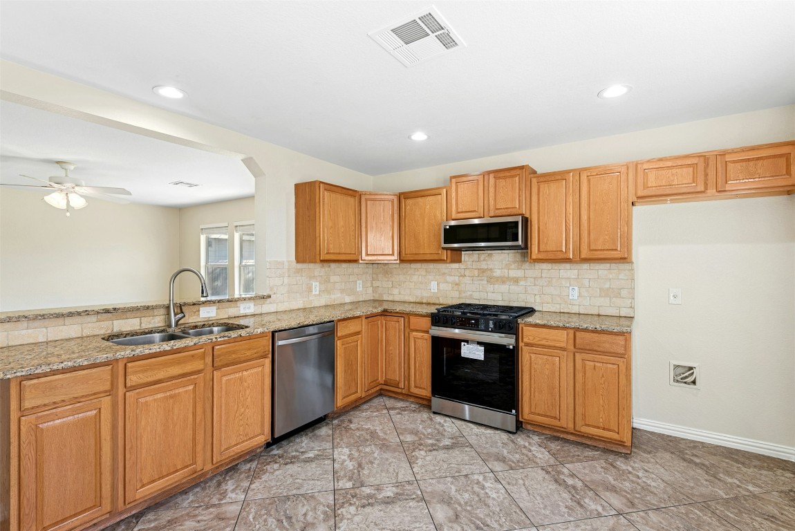 17913 Honey Locust Lane Elgin, TX 78621 - Photo 6 of 31 a kitchen with stainless steel appliances granite countertop a sink stove refrigerator and cabinets