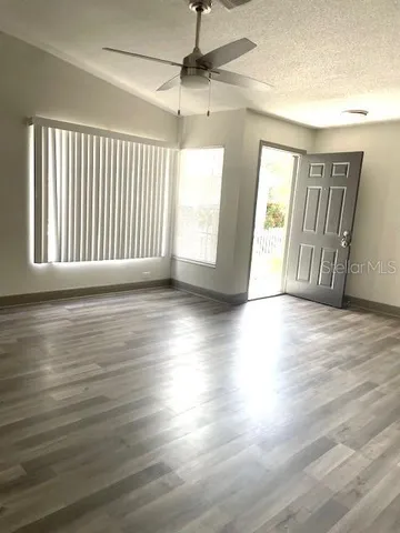an empty room with wooden floor and windows