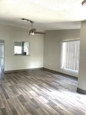 a view of empty room with wooden floor and fan