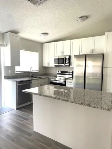 a kitchen with kitchen island granite countertop a sink a stove a microwave a center island and stainless steel appliances