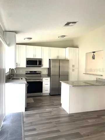 a kitchen with stainless steel appliances a refrigerator a sink and wooden floors