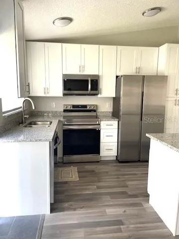 a kitchen with kitchen island granite countertop a stove a sink and a refrigerator