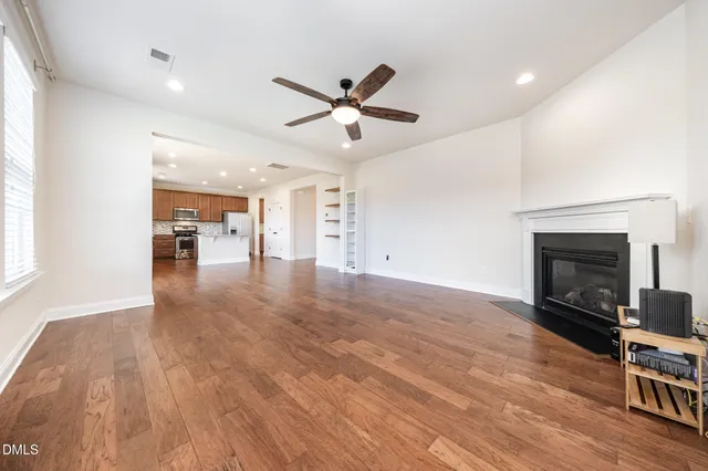 an empty room with wooden floor a fireplace and windows