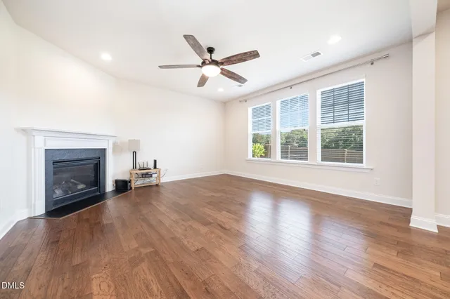 an empty room with windows fireplace and wooden floor