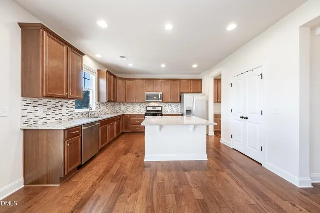 a kitchen with a sink wooden floor cabinets and a window