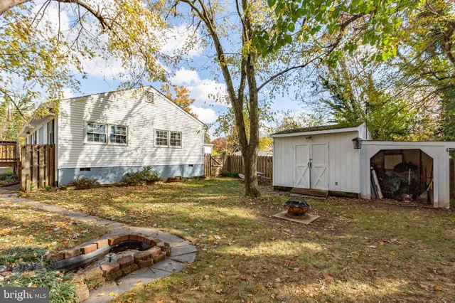 a backyard of a house with a large tree and wooden fence