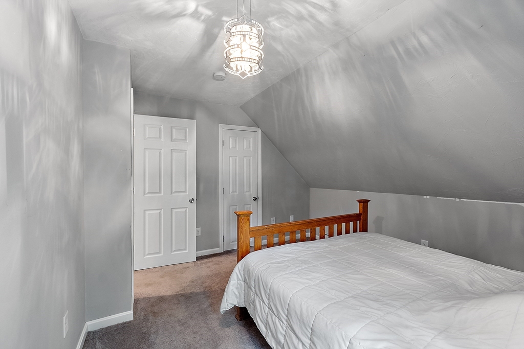 506 Pleasant Street Gardner, MA 01440 - Photo 32 of 41 a bedroom with a bed and a chandelier
